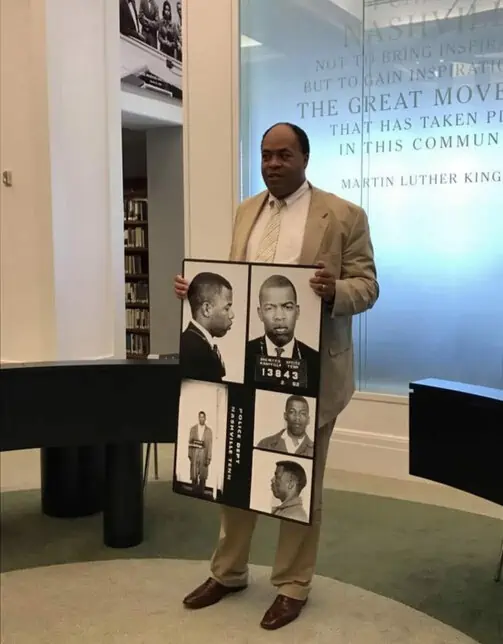 Man presenting a board with historical black-and-white portraits.