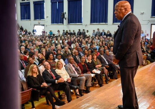 A speaker addressing a large audience in an auditorium.