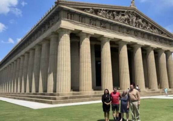 Group of people posing in front of a large classical temple.