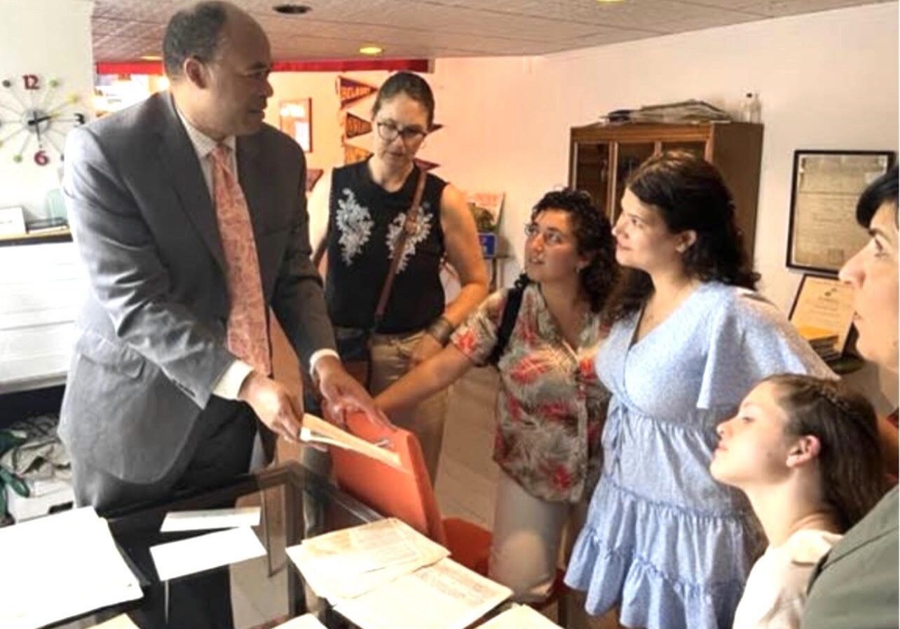 A man shows documents to a group of women in a lively discussion.
