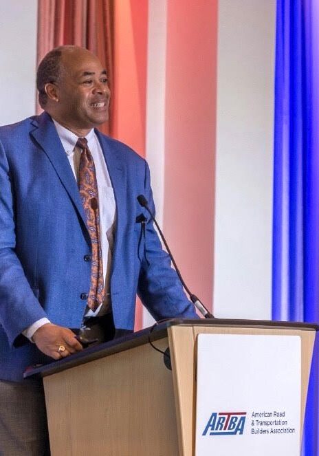 Man in a blue suit speaking at a podium.