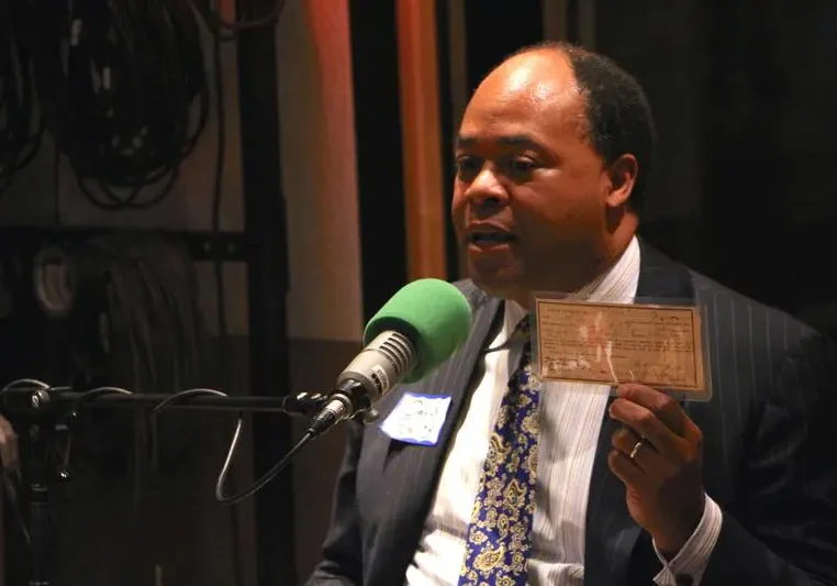 Man speaking into a microphone while holding a card.
