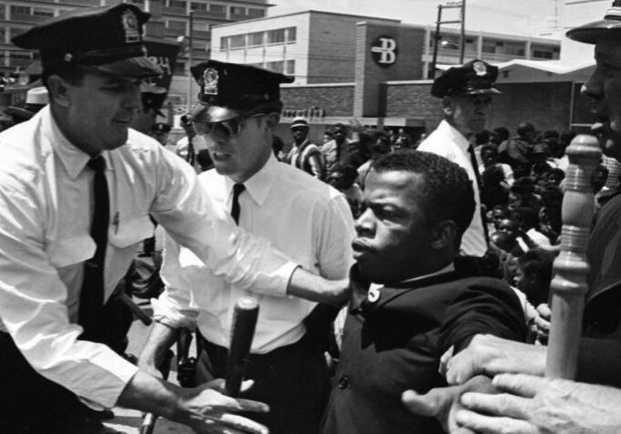 Civil rights protester being restrained by police officers in a tense moment.