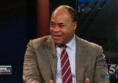 Man in a suit talking and smiling during a conversation.