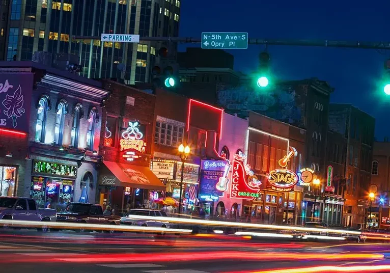 Vibrant city street at night with colorful neon signs and light trails.