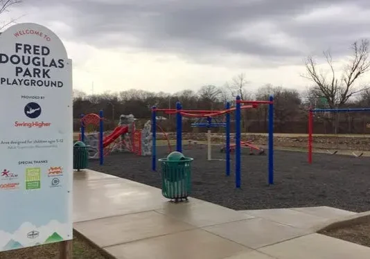 Empty playground with slides and climbing structures under a cloudy sky.