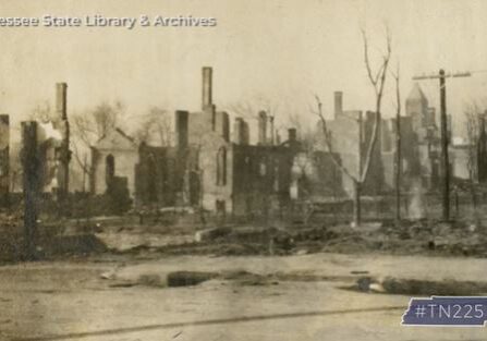 Ruins of a building after a fire, surrounded by leafless trees.