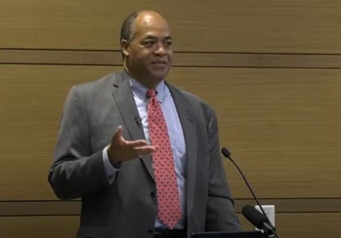 Man in suit speaking at a podium.