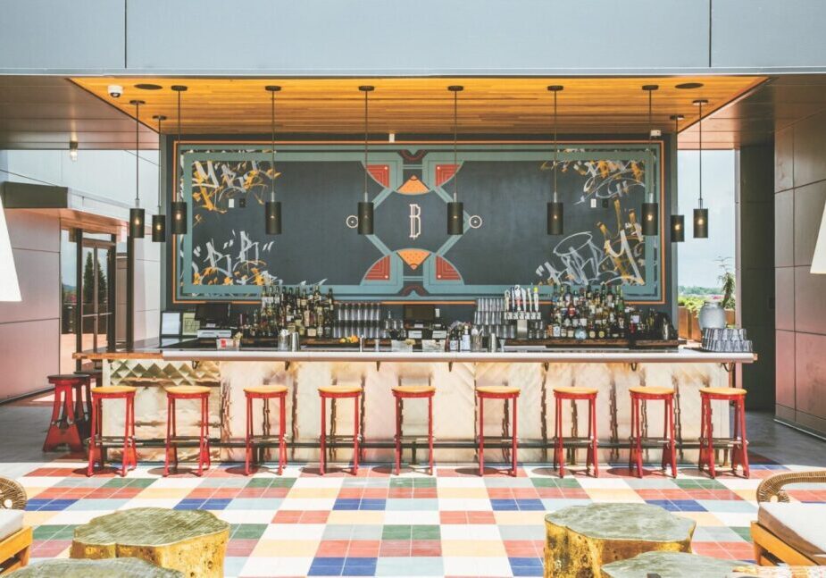 Modern bar with colorful tiled floor and elegant lighting.